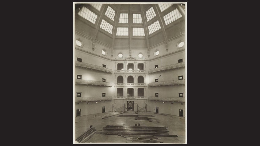 black border with sepia photo of domed reading room under construction