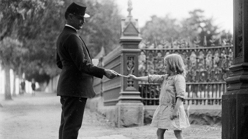 A man in uniform hands a letter to a small girl