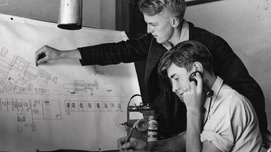 Two young men scrutinise a large map