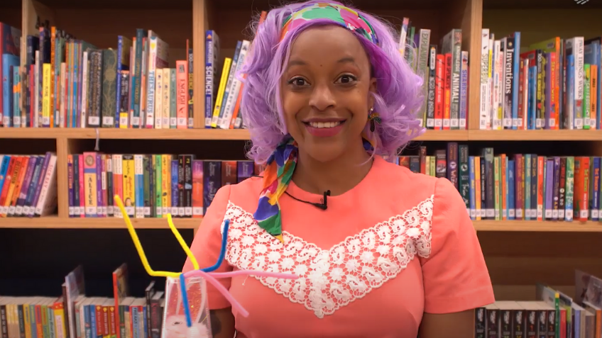 Woman in pink top smiling and holding a craft spaceship