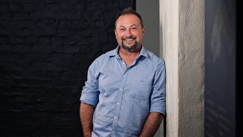 Man leaning on a wall and smiling at the camera