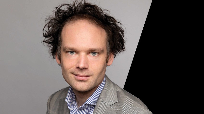 Headshot of Erik Jensen on grey and black background