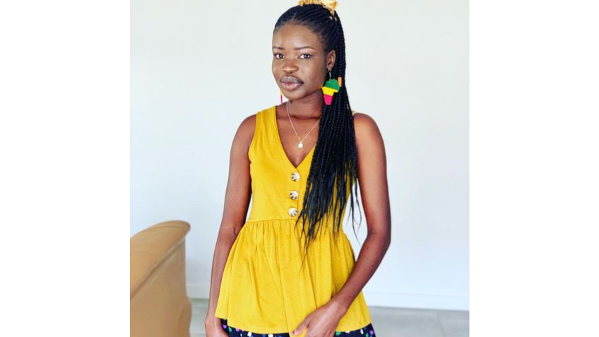 Author Flora Chol wearing a yellow top and colourful earrings.
